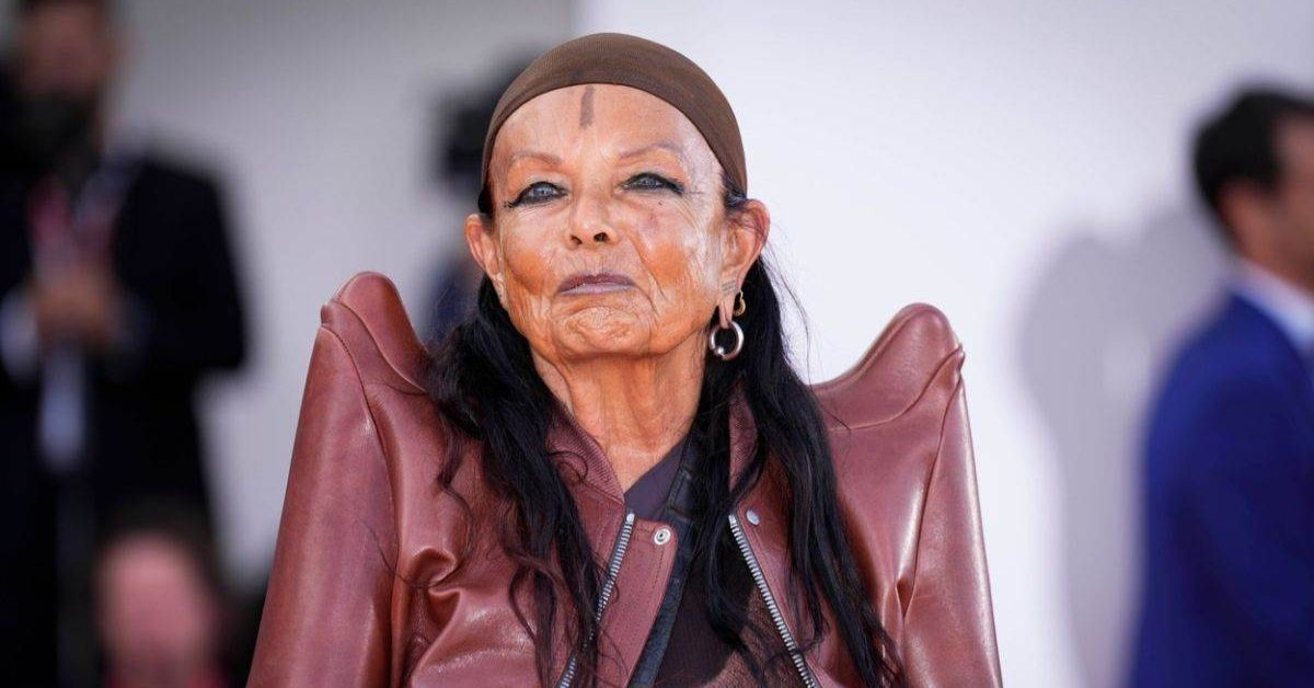 Michele Lamy standing confidently in avant-garde attire, highlighting her iconic fashion style and creative presence.