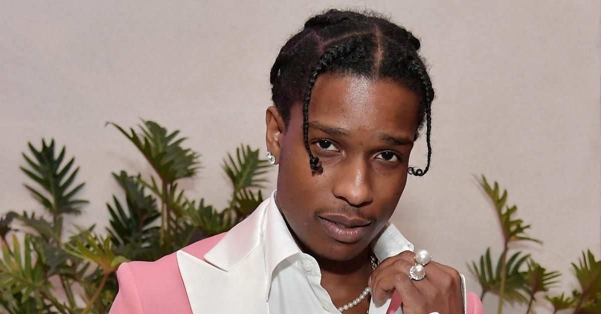 A$AP Rocky performing on stage wearing stylish designer clothes, representing his success as a Harlem rapper and fashion icon.